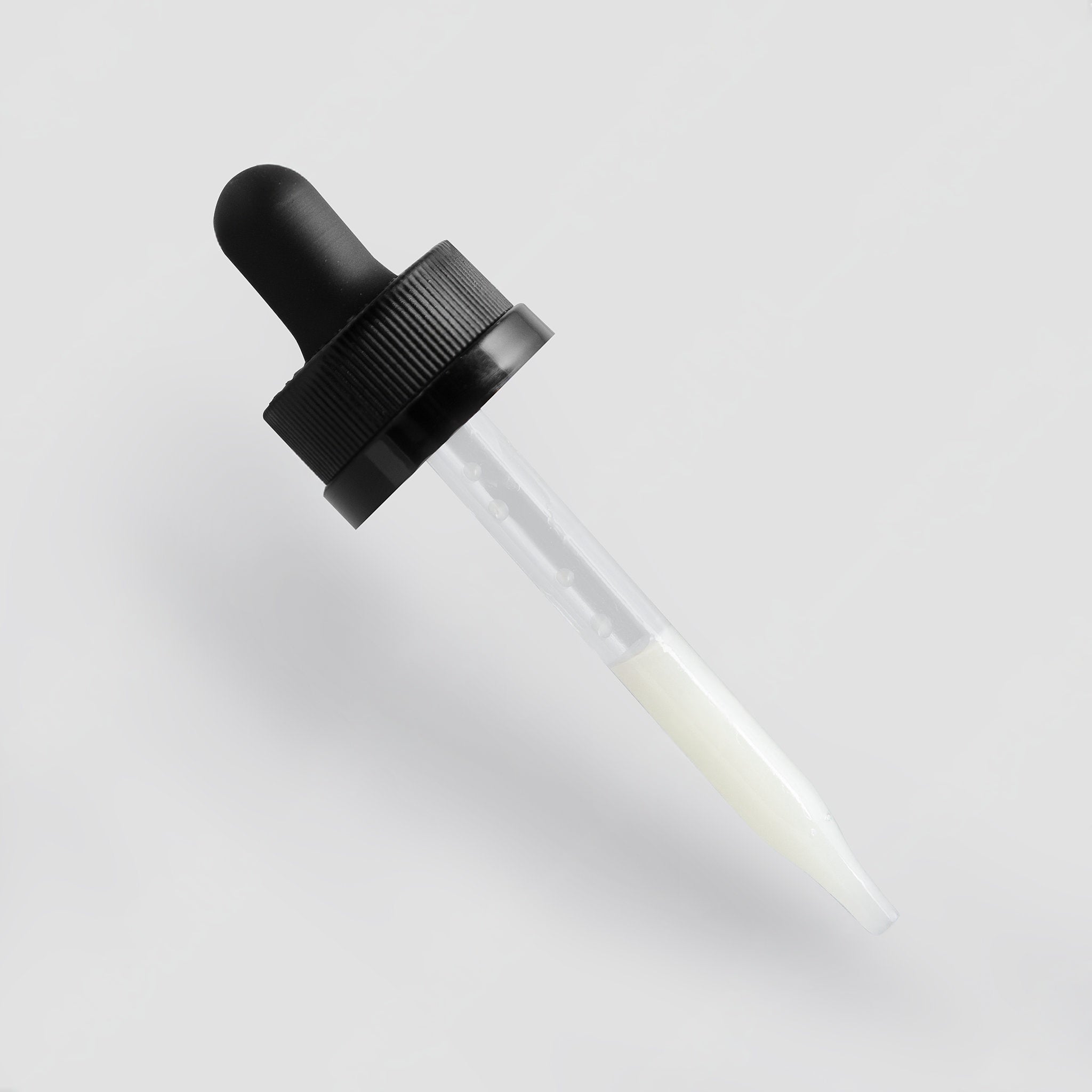 Glass dropper bottle with black cap on a light gray background