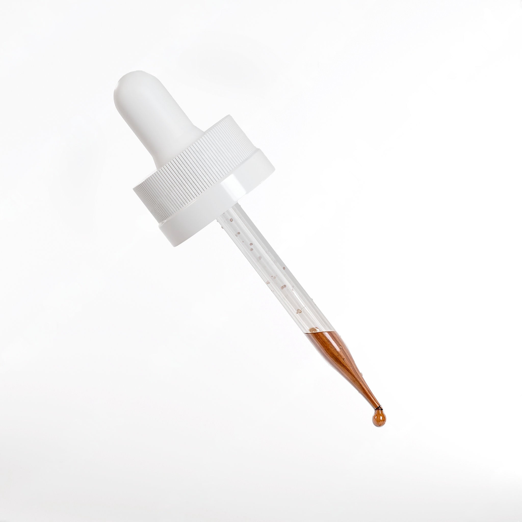 White dropper with brown liquid on a white background