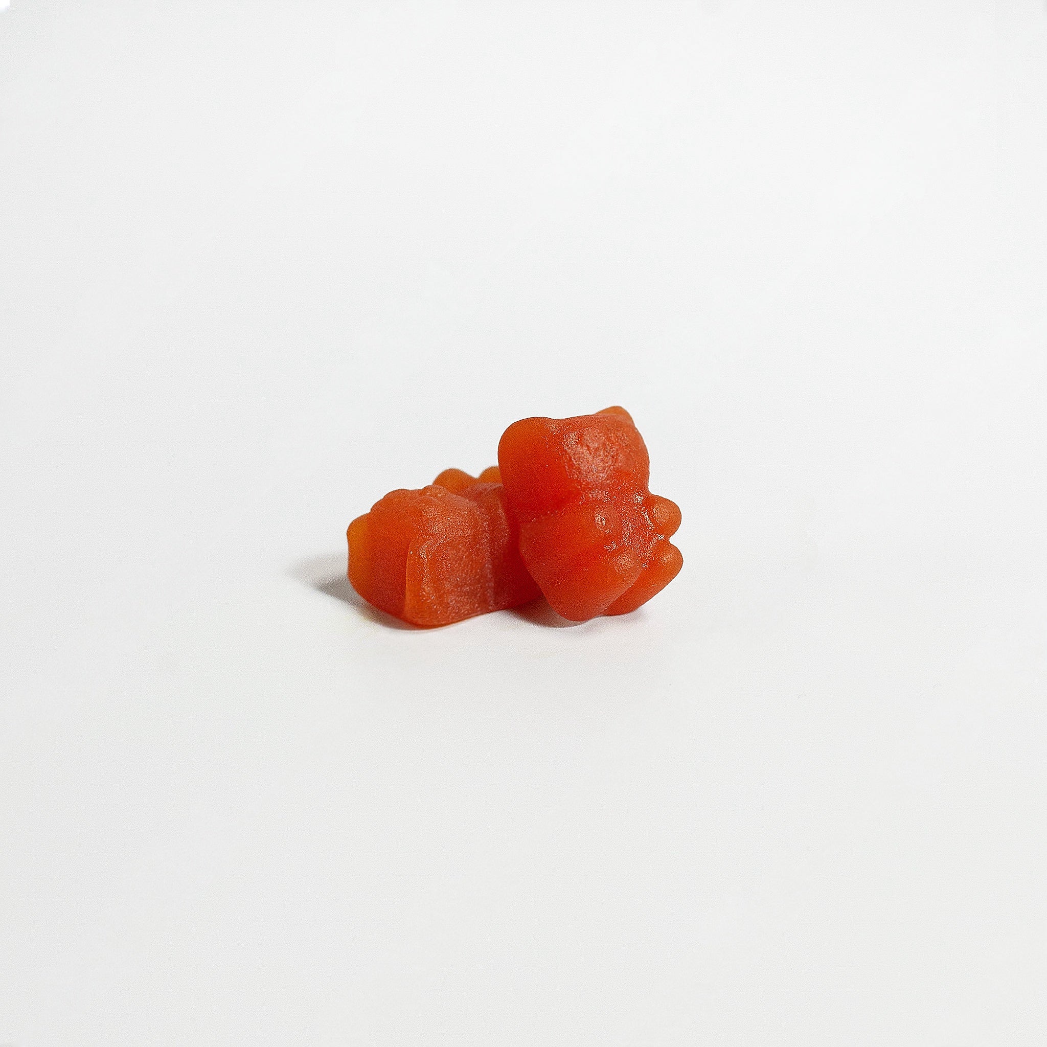 Two orange cat-shaped gummy candies on a white background